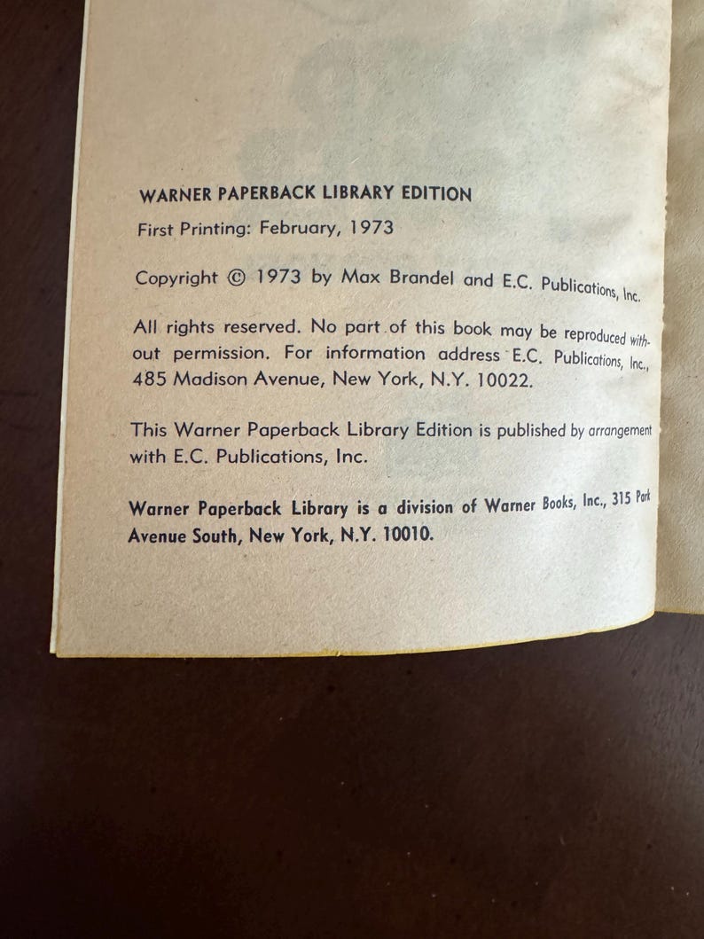Pode incluir: Um close-up de uma p&aacute;gina de livro com texto de uma edi&ccedil;&atilde;o da Warner Paperback Library. O texto inclui as informa&ccedil;&otilde;es de direitos autorais de 1973, a data da primeira impress&atilde;o de fevereiro de 1973 e o endere&ccedil;o da editora em Nova York.