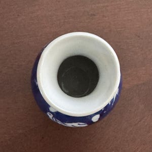 May include: A small, blue and white ceramic vase with a wide opening. The vase has a floral design.