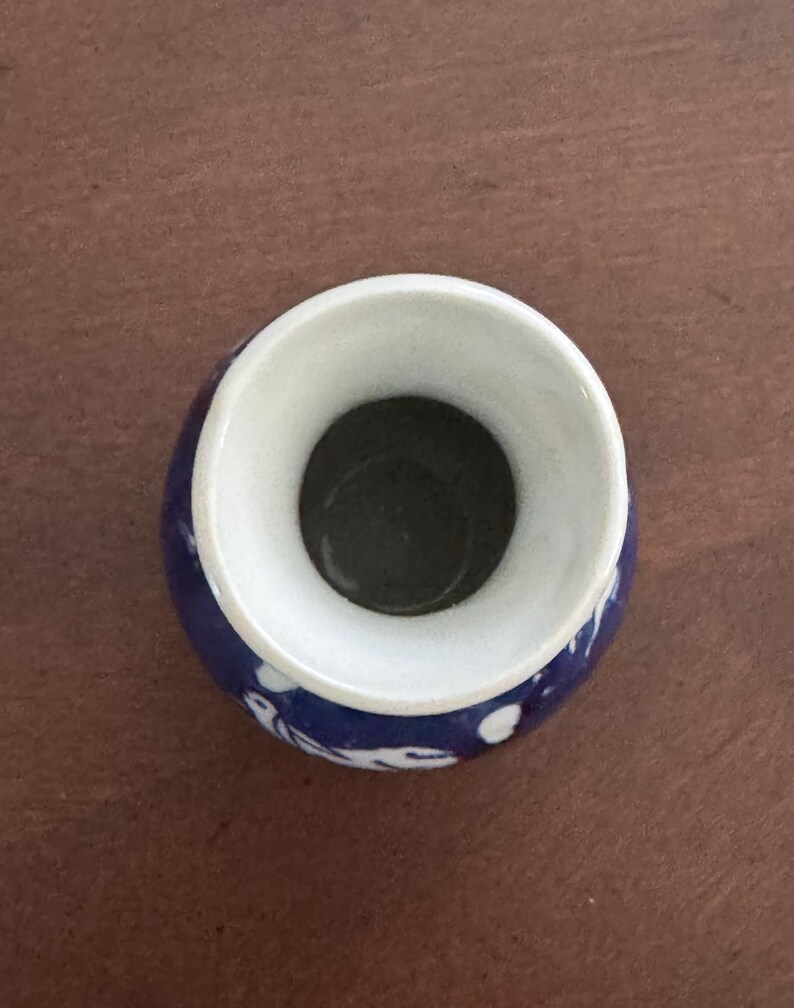 May include: A small, blue and white ceramic vase with a wide opening. The vase has a floral design.