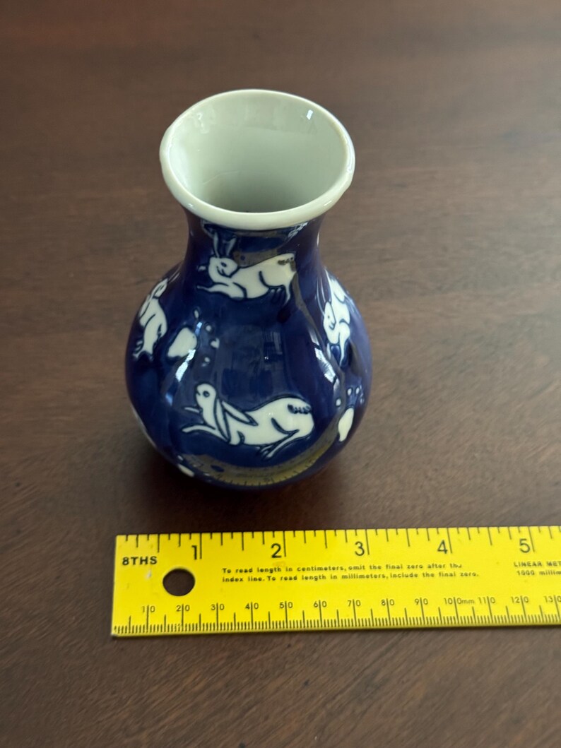 May include: A small blue and white ceramic vase with a white rabbit design. The vase is about 4 inches tall.