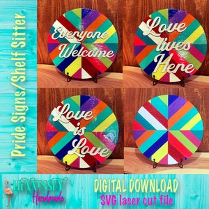 May include: Four round wooden signs with a colorful geometric pattern. The signs feature the text "Everyone Welcome", "Love lives Here", "Love is Love", and a blank sign. The signs are perfect for a shelf sitter or a pride display.