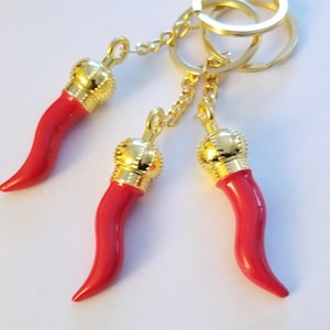 May include: Three red and gold Italian horn keyrings with a gold chain and three gold key rings.