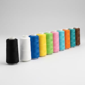 May include: A row of eleven cylindrical spools of sewing thread arranged diagonally. The colors include black, white, blue, yellow, lime green, pink, light blue, orange, teal, and brown, each wound onto a white plastic core.