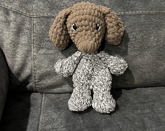 May include: A brown and white crocheted stuffed dog toy sitting on a gray couch.