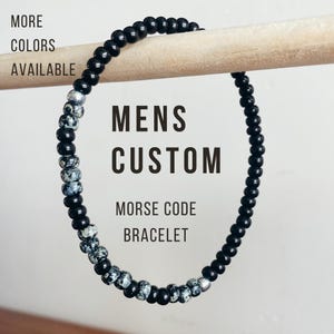 May include: A black and white beaded bracelet with the text "Mens Custom Morse Code Bracelet".