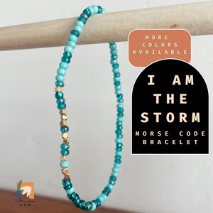 May include: A turquoise and gold beaded bracelet with the text "I AM THE STORM" and "MORSE CODE BRACELET".  More colors are available.
