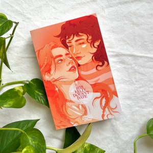May include: A book cover with an illustration of two people with red hair. The title of the book is "Iris Kelly Doesn't Date" and the author is Ashley Herring Blake.