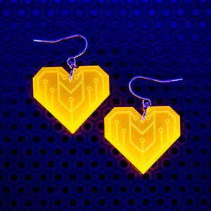 May include: A pair of yellow heart-shaped earrings with a circuit board design. The earrings are made of acrylic and have silver hooks.