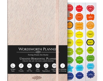 May include: A pink and gold horizontal planner with the words "WORDSWORTH PLANNER" and "Turning Dreams Into Reality" on the cover. The planner has a black spine and a ribbon bookmark. The planner is surrounded by colorful stickers with motivational phrases.