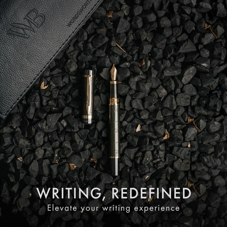 Puede incluir: Una pluma estilogr&aacute;fica negra y dorada con un patr&oacute;n decorativo en el cuerpo. La pluma est&aacute; sobre un lecho de grava negra. El texto "WRITING, REDEFINED" y "Elevate your writing experience" est&aacute; debajo de la pluma.