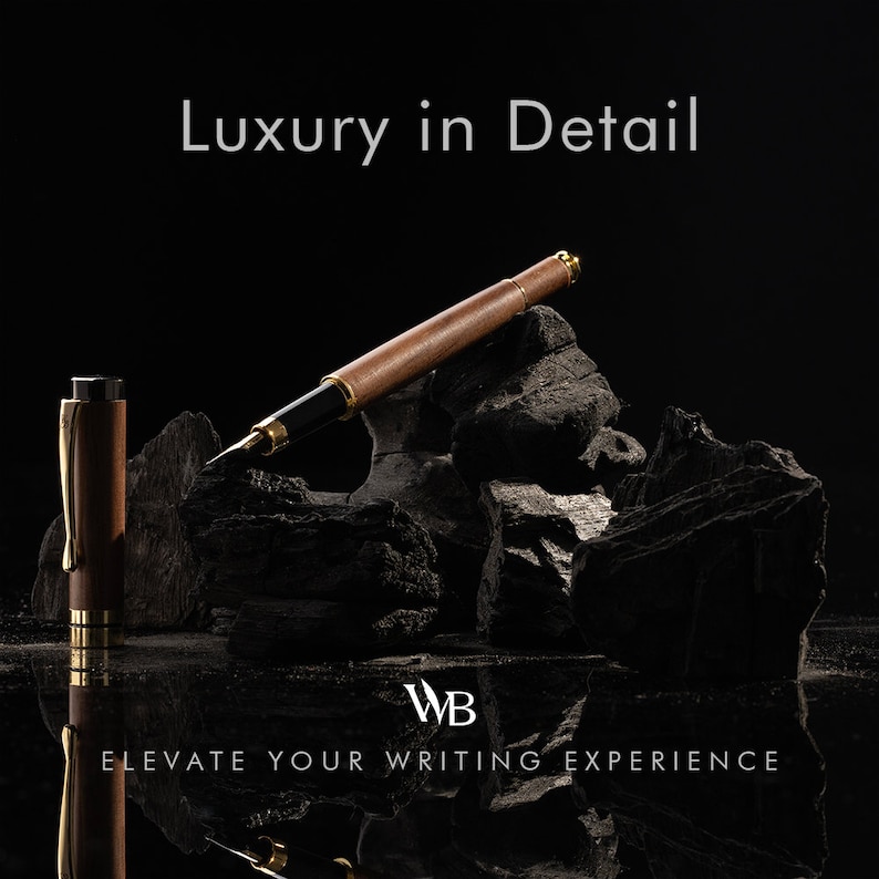 Op de afbeelding: Een bruine en gouden vulpen met een houten vat en gouden accenten ligt op een stapel zwarte houtskoolstenen. De tekst "Luxury in Detail" staat boven de pen, en de tekst "WB Elevate Your Writing Experience" staat onder de pen.