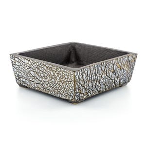 May include: Square ceramic planter with a textured, crackled white and grey exterior. The interior is dark grey. The planter has a low profile and sits on small feet. Suitable for succulents or small plants.