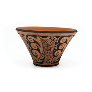 May include: A wide, conical terracotta bowl featuring a black painted rim and intricate black geometric patterns. The exterior surface displays repeating spiral motifs, triangular shapes, and linear cross-hatching designs against the natural clay.
