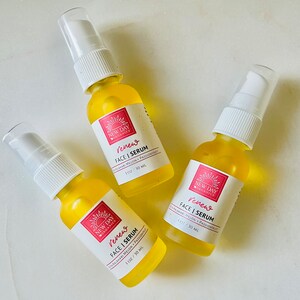Puede incluir: Tres peque&ntilde;os frascos de suero amarillos con tapas de pulverizaci&oacute;n blancas est&aacute;n dispuestos sobre una superficie blanca. Cada frasco tiene una etiqueta con el texto "Renew FACE | SERUM" y "1 OZ / 30 ML". Las etiquetas tambi&eacute;n incluyen las palabras "NEW DAY ORGANICS".