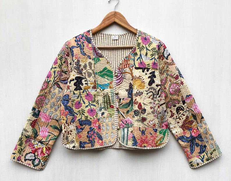 May include: A cream-colored quilted jacket with a floral print in shades of pink, blue, green, and yellow. The jacket has a V-neck and long sleeves.