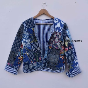 May include: A blue and white patchwork jacket with a floral print. The jacket has a V-neck and long sleeves. The fabric is quilted and has a striped pattern on the inside.