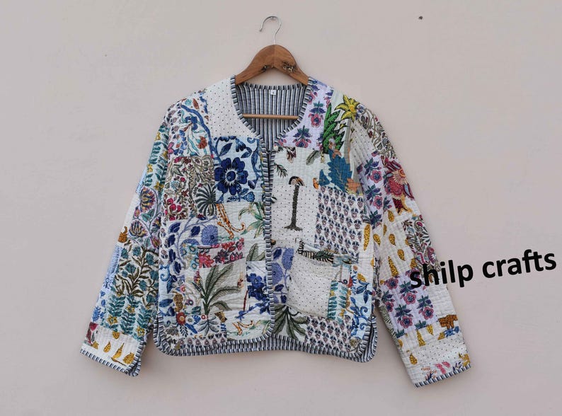 May include: A white quilted jacket with a patchwork design featuring floral and geometric patterns in shades of blue, green, and pink. The jacket has a button closure and a pocket on the left side. The text "shilp crafts" is visible on the right side of the jacket.