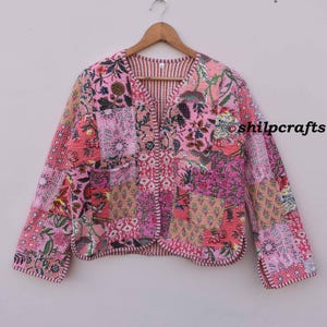 Peut inclure: Une veste matelassée rose avec un motif patchwork floral. La veste a un col en V et des manches longues. Le tissu est doux et confortable. La veste est parfaite pour superposer au printemps ou à l'automne.