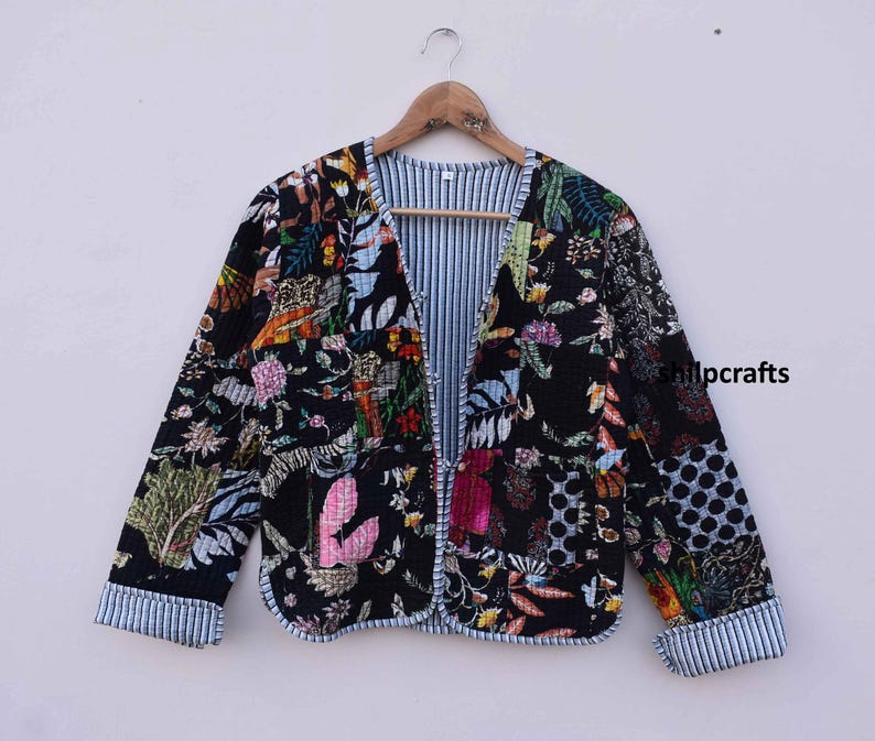 May include: A black quilted jacket with a floral print. The jacket has a V-neck and a striped lining.