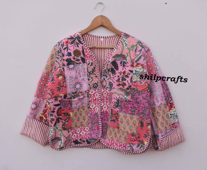 May include: A pink and floral patchwork jacket with a V-neck and long sleeves. The jacket has a quilted design and a slightly cropped length. The text "shilpcrafts" is visible on the right side of the jacket.