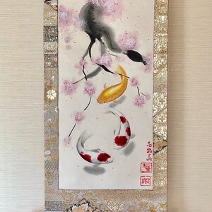 May include: Japanese scroll painting featuring a black bird perched on a cherry blossom branch, with two koi fish swimming below. The artwork is framed with gold and patterned fabric, and includes Japanese characters.