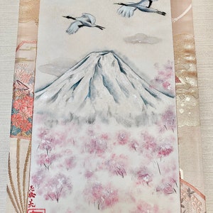 May include: A rectangular painting shows Mount Fuji, cherry blossom trees, two cranes, and a full moon. The artwork uses a soft palette of white, grey, and pink. Japanese characters are visible in the lower left corner.