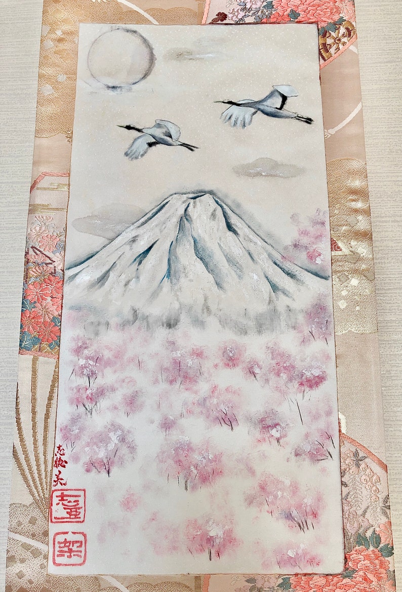 May include: A rectangular painting shows Mount Fuji, cherry blossom trees, two cranes, and a full moon. The artwork uses a soft palette of white, grey, and pink. Japanese characters are visible in the lower left corner.