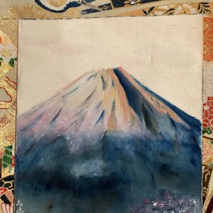 May include: An original painting of Mount Fuji. The artwork depicts the iconic mountain with a snow-capped peak, painted in shades of blue, pink, and white. The painting is on a textured canvas, with a signature in the lower left corner.