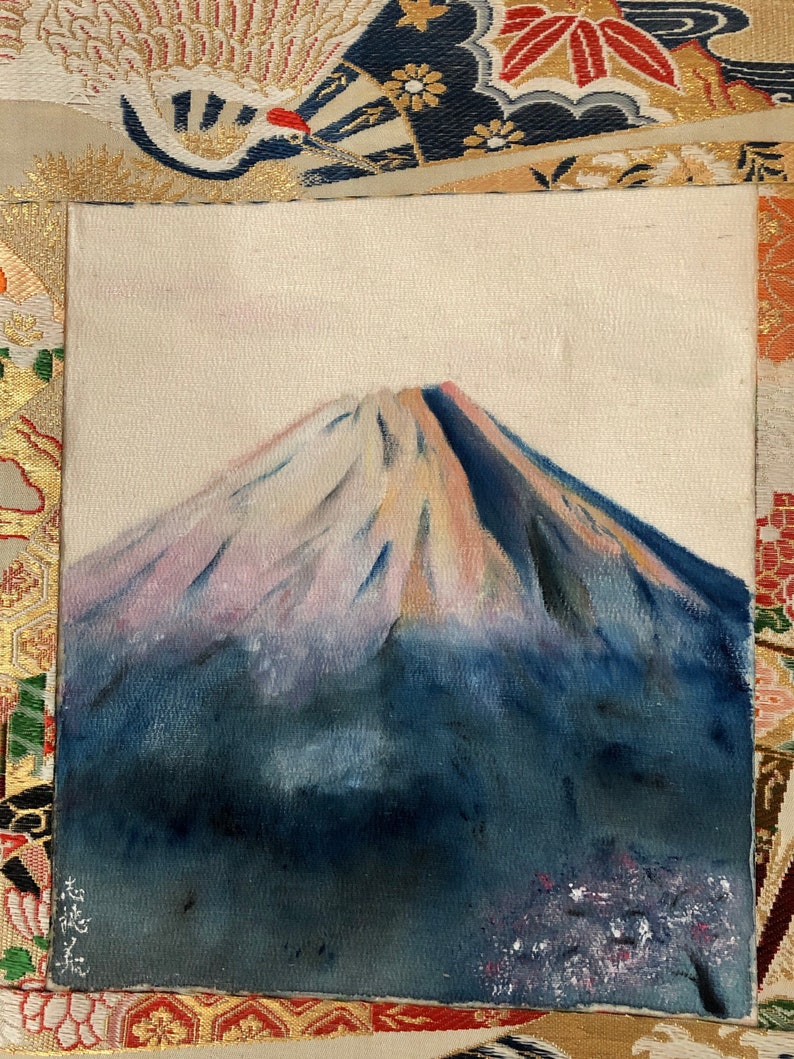 May include: An original painting of Mount Fuji. The artwork depicts the iconic mountain with a snow-capped peak, painted in shades of blue, pink, and white. The painting is on a textured canvas, with a signature in the lower left corner.