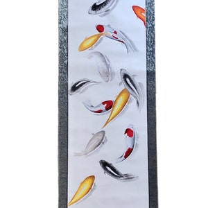 May include: Vertical scroll painting featuring koi fish in a pond. The artwork showcases colorful fish in shades of gold, red, black, and white, set against a white background. The scroll has a gray border and wooden accents.