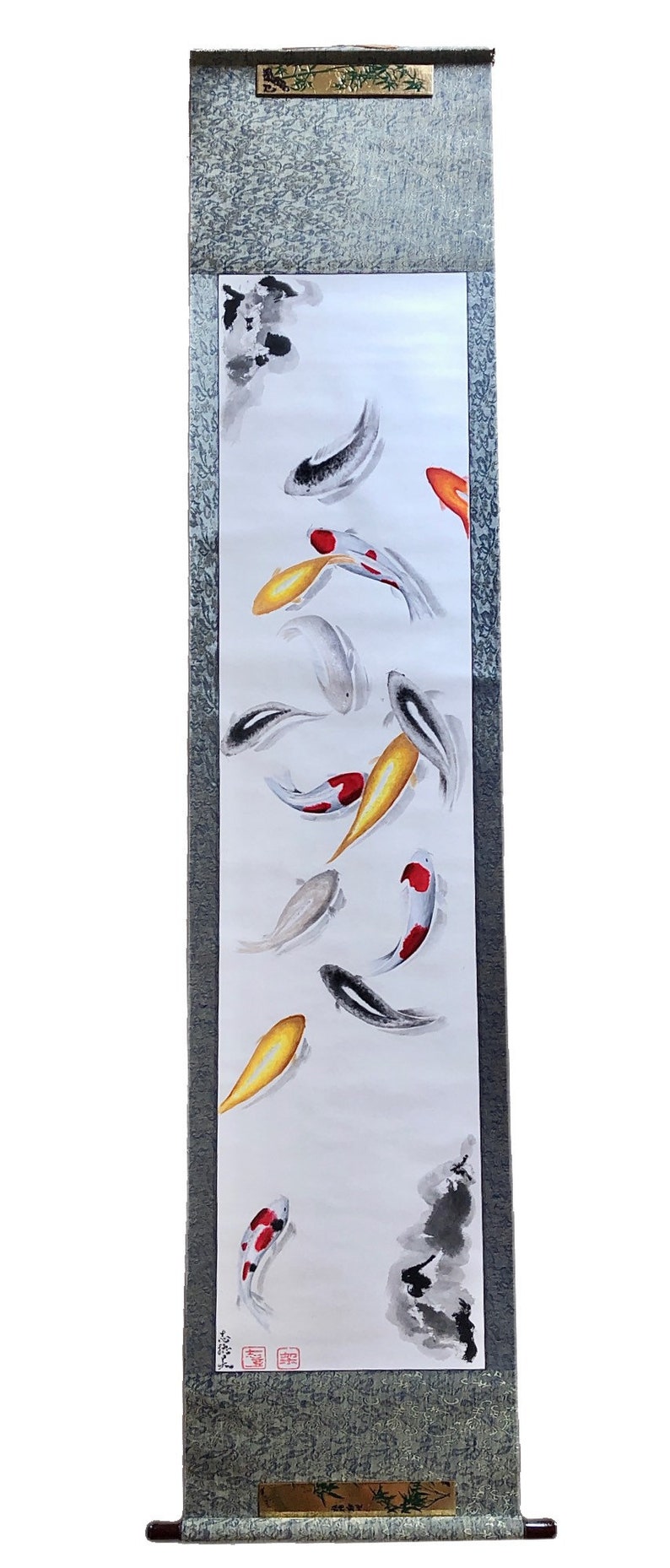 May include: Vertical scroll painting featuring koi fish in a pond. The artwork showcases colorful fish in shades of gold, red, black, and white, set against a white background. The scroll has a gray border and wooden accents.
