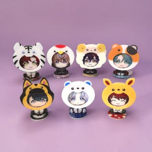 May include: Seven acrylic character stands featuring anime-style faces framed by colourful animal-themed hoods. The designs include a white tiger, a chicken, a ram, a guinea pig, a black and yellow cat, a white bear, and a yellow rabbit-eared hood.