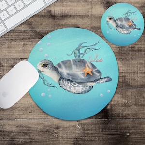 May include: Round mousepad and coaster set featuring a watercolor sea turtle design. The turtle is gray and white with a starfish on its shell, surrounded by seaweed and bubbles against a blue background. The mousepad is round, and the coaster is a smaller matching circle.