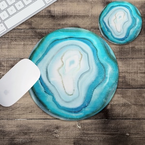 May include: A blue and white agate-style mouse pad with a circular design. The mouse pad is on a wooden surface.
