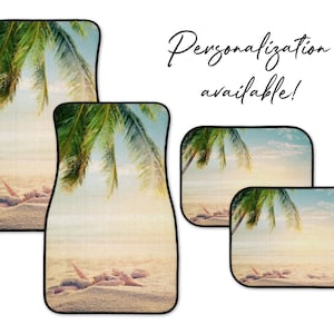 May include: Set of four car floor mats with a tropical beach scene featuring a palm tree, blue sky, and white sand. The mats have black borders.