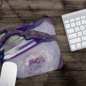 May include: Purple and white agate mouse pad with a swirling pattern. The mouse pad is on a wooden surface.
