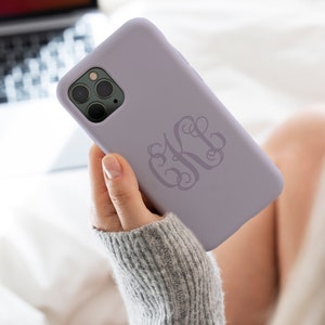 May include: A lavender phone case with a monogrammed design. The monogram is in a script font and is the letters "KH".