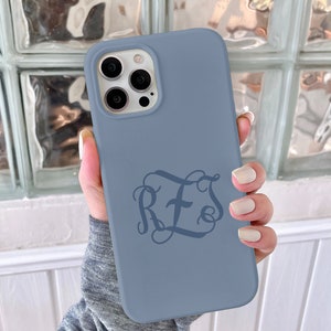 May include: A blue silicone phone case with a monogram design featuring the letters "RFS" with a cross in the middle.