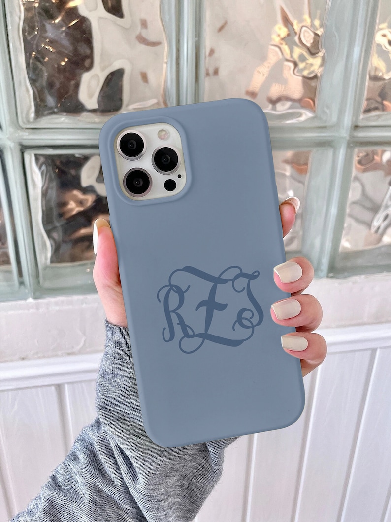 May include: A blue silicone phone case with a monogram design featuring the letters "RFS" with a cross in the middle.