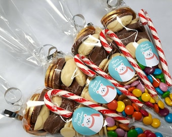 Puede incluir: Bolsas transparentes de celofán llenas de caramelos navideños variados. Las bolsas contienen monedas de chocolate, chocolate blanco, caramelos de colores y bastones de caramelo. Cada bolsa tiene una etiqueta azul con un oso polar y "Feliz Navidad".