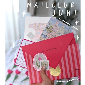 Könnte beinhalten: Ein rot-rosa gestreifter Umschlag mit einem Blumenaufkleber und einem goldenen Siegel. Der Umschlag ist Teil eines Mailclubs, mit dem Text "MAILCLUB JUNI" oben. Mehrere illustrierte Karten sind sichtbar.