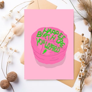 May include: Pink birthday card with a green cake that says "Happy Birth Day You Wizard".
