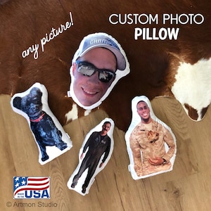 Pu&ograve; includere: Quattro cuscini personalizzati con foto su un tappeto di pelle di mucca marrone e bianco. I cuscini mostrano il viso di un uomo, un uomo in uniforme militare, un uomo in uniforme da pilota e un cane nero. I cuscini sono bianchi con un bordo bianco. Il testo "CUSTOM PHOTO PILLOW" &egrave; scritto in nero nella parte superiore dell'immagine.