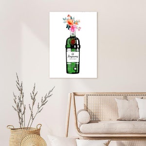 May include: A green glass bottle of Tanqueray London Dry Gin with a bouquet of pink and orange flowers on top. The bottle has a white label with the brand name and "London Dry Gin" printed on it.
