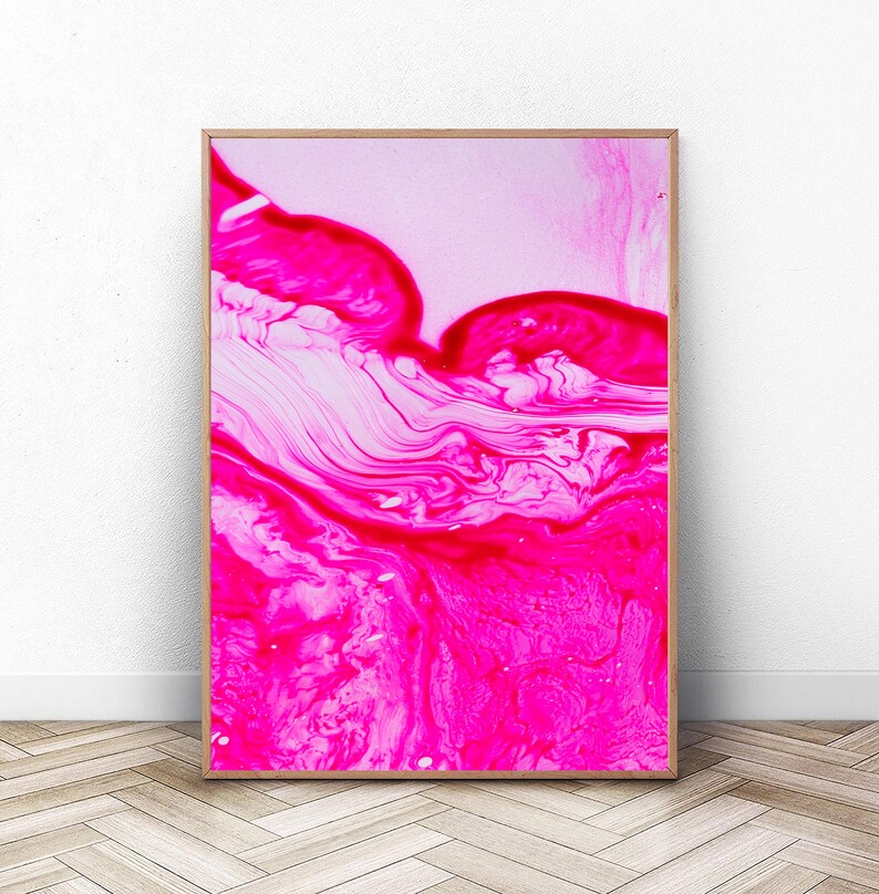K&ouml;nnte beinhalten: Abstrakter Kunstdruck mit einem pinkfarbenen und wei&szlig;en Wirbelmuster. Der Druck ist in einem hellen Holzrahmen gerahmt.
