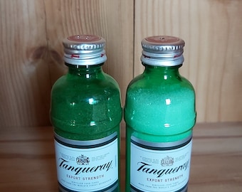 May include: Two miniature green glass bottles with silver lids and red labels. The labels read "Tanqueray Export Strength London Dry Gin Duty Free".