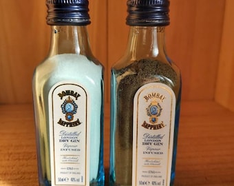 May include: Two miniature bottles of Bombay Sapphire London Dry Gin, each with a blue label and gold lettering. The bottles are 50 ml and 40% alcohol by volume.