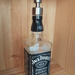 May include: A clear glass bottle with a black label that reads "Jack Daniel's Old No.7 Brand Tennessee Sour Mash Whiskey". The bottle has a stainless steel soap dispenser pump on top.