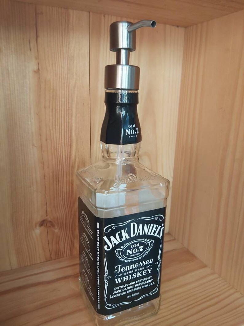 May include: A clear glass bottle with a black label that reads "Jack Daniel's Old No.7 Brand Tennessee Sour Mash Whiskey". The bottle has a stainless steel soap dispenser pump on top.