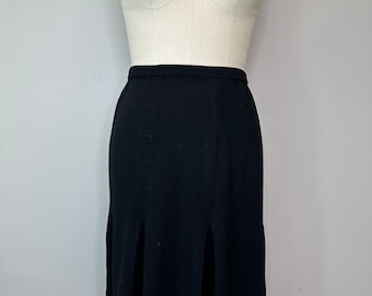 May include: A black midi skirt with a pleated design. The skirt is knee-length and has a fitted waistband.